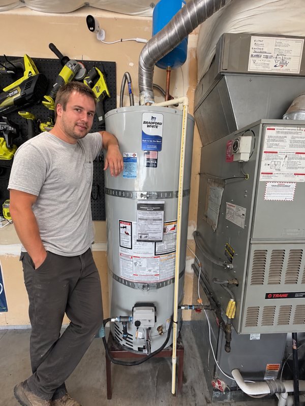 Jeremy, owner of Jeremy's Plumbing, beside a Bradford White gas water heater he installed in Vancouver, WA
